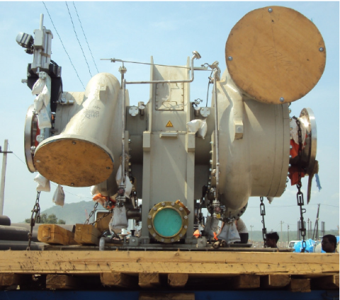 Eine große industrielle Ventilbaugruppe mit mehreren Rohren und Komponenten, die auf einer hölzernen Plattform auf einem Schiff befestigt sind.